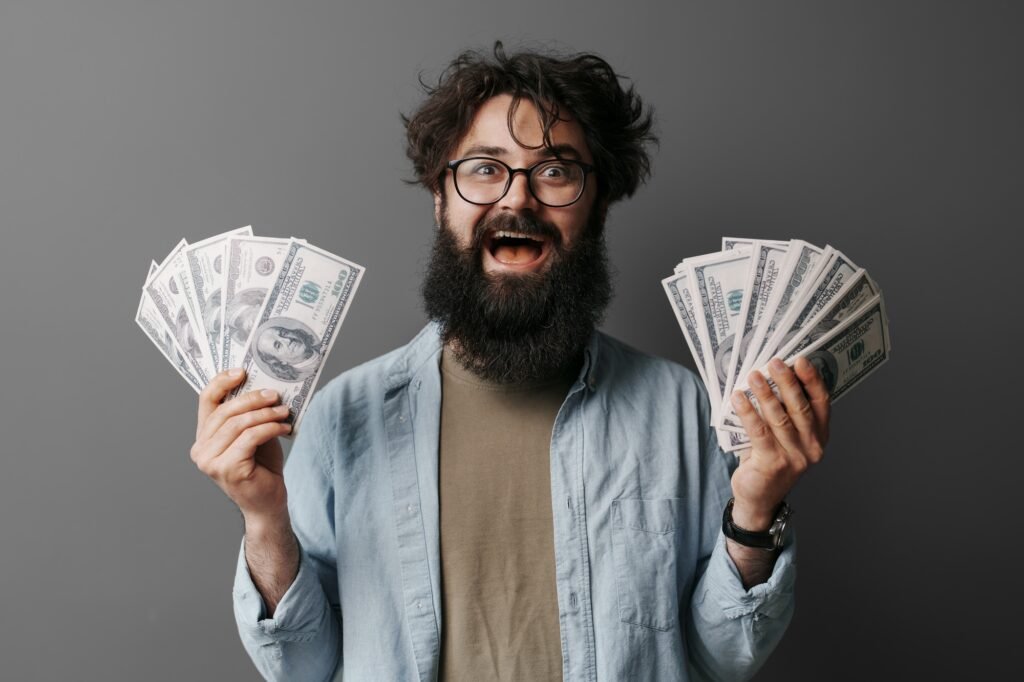 Bearded man excitedly holding multiple cash bills